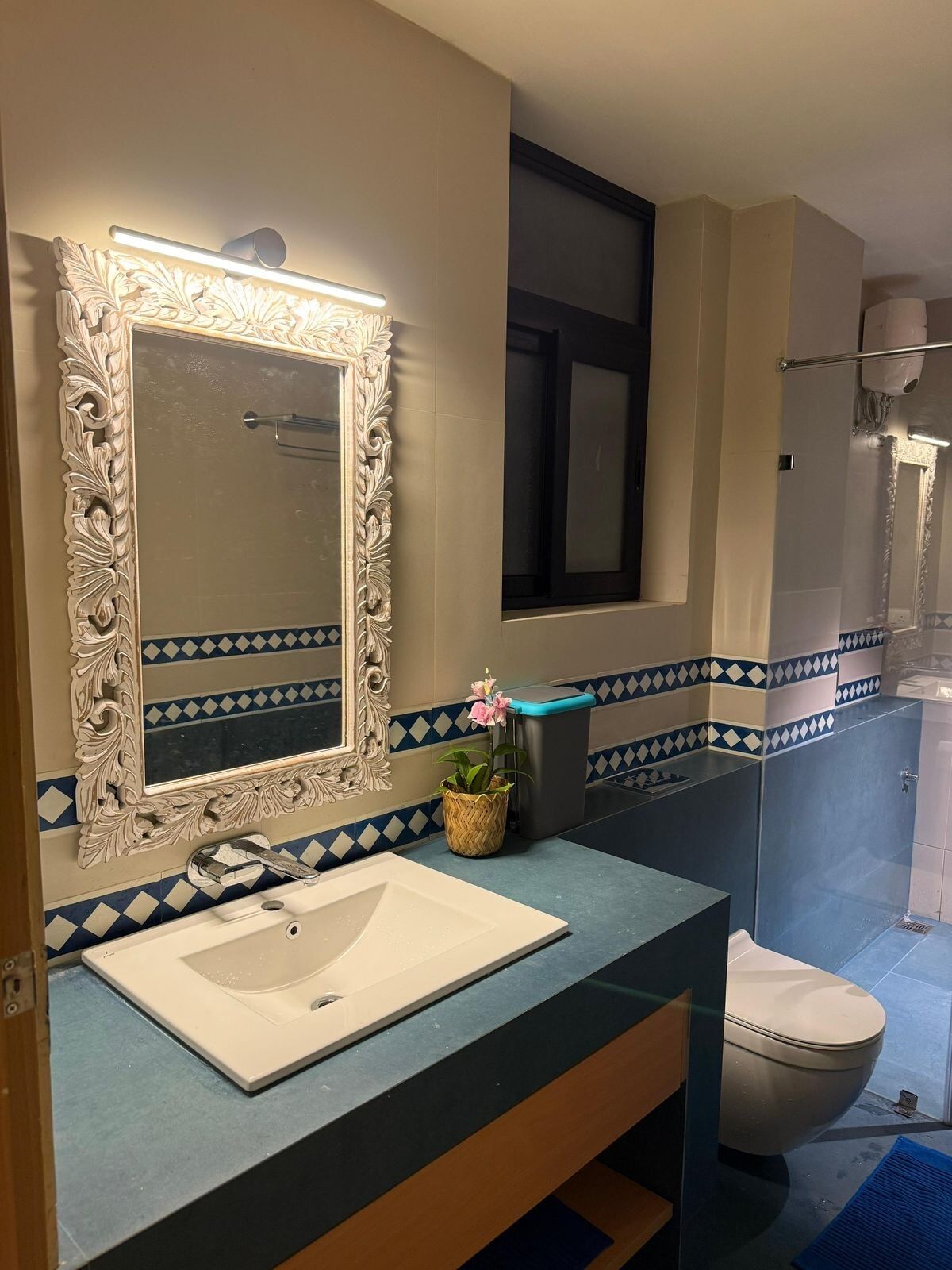 A bathroom with a patterned tile dado and a carved mirror.
